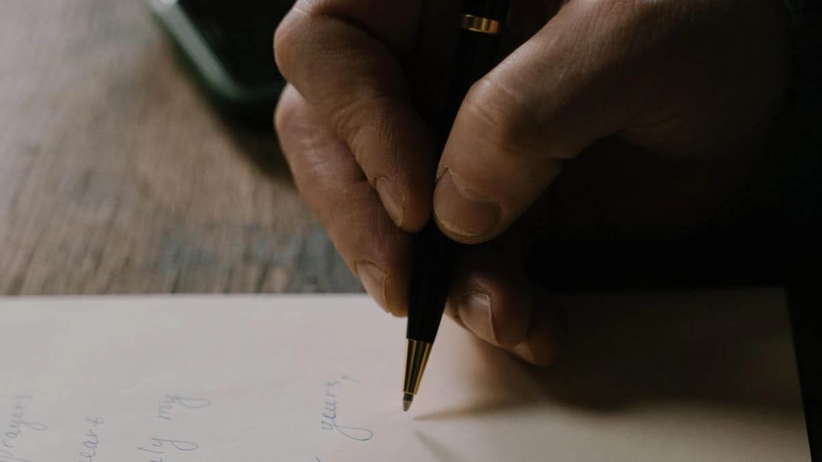 close up pen in fingers writing a letter